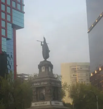 Cuauhtémoc Monument on a carved stone pedestal with a tall figure holding a staff or spear.