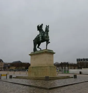 Equestrian Statue of Louis XIV on a tall stone pedestal in front of the Palace of Versailles.