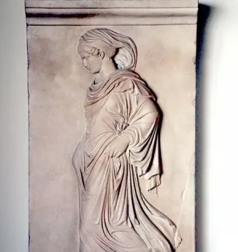 Gradiva relief showing a female figure in profile walking with one foot raised and draped in flowing garments.