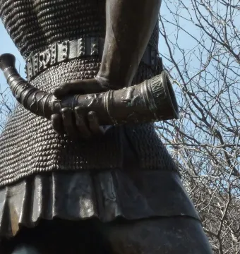 Close-up of Leif, the Discoverer showing bronze chainmail armor and an ornate horn-shaped object in his hand.