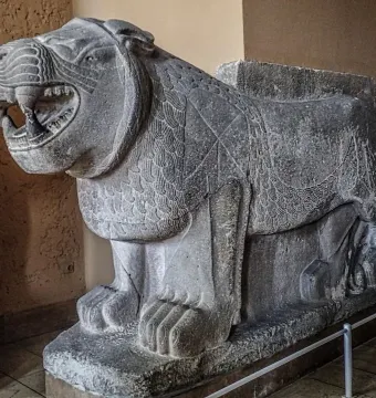 Weathered stone Sam\'al lion sculpture with an open mouth and carved mane