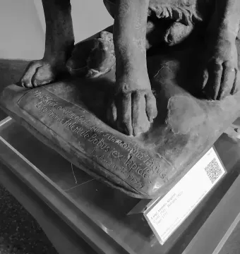 Lower part of Cane Tago, showing the dog sculpture’s four paws on a carved base.