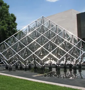 Delta Solar sculpture with reflective triangular panels rising above a dark pool of water.