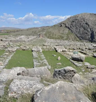 Hattusa green stone block standing among ancient grey stone ruins and patches of grass