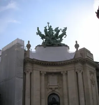 Immortality Overtaking Time sculpture atop the Grand Palais, with a teal chariot and four horses above the building\'s central entrance.