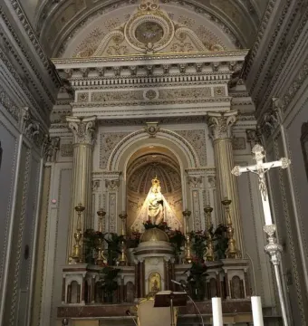 Crowned statue of Madonna dell\'Udienza in an ornate church niche above a marble altar.