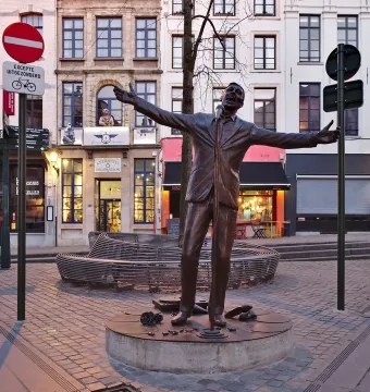 L\'Envol bronze sculpture of a man in a suit singing into a microphone with his arms outstretched in a cobblestone square.