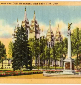Seagull Monument with a golden bird sculpture on top of a tall white base in a landscaped park setting.