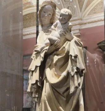 Krumlov Madonna statue of a mother holding a child, shown in a museum display case.