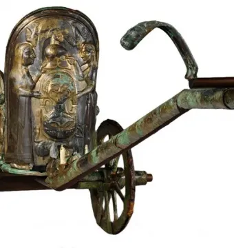 The Monteleone Chariot with ornate bronze relief figures and a central mask-like design on the front panel.