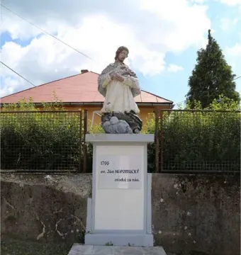 Stone statue of St. John of Nepomuk on a tall inscribed pedestal with three steps in front.