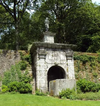 Vénus de Quinipily stone monument with a small figure set in an ivy-covered wall