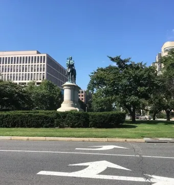 Winfield Scott statue on horseback on a pedestal in a grassy area with trees and buildings behind it.