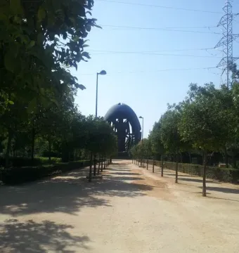 Birth of a New Man sculpture in the distance at the end of a dirt path lined with trees.