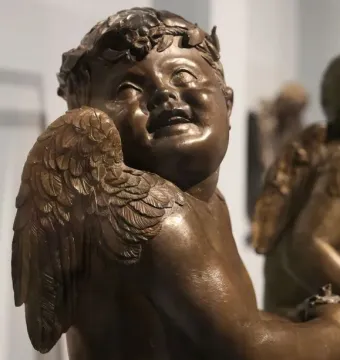 Close-up of Donatello’s bronze candelabra angel with a leafy wreath, feathered wings, and an open mouth.