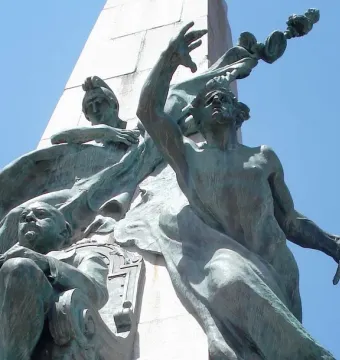 Bronze figures on the Monumento a Júlio de Castilhos, including a seated figure and a draped figure reaching upward beside a stone pillar.