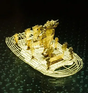 The Muisca Raft, a small gold raft sculpture with several figures standing on deck.