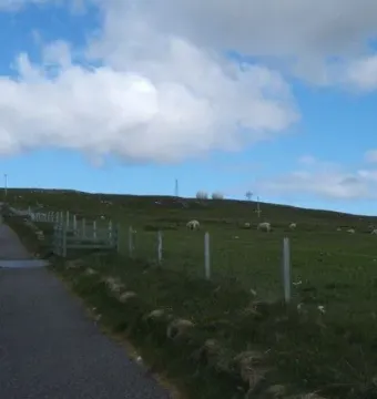 Our Lady of the Isles standing on a grassy hill with a paved path leading up to it.
