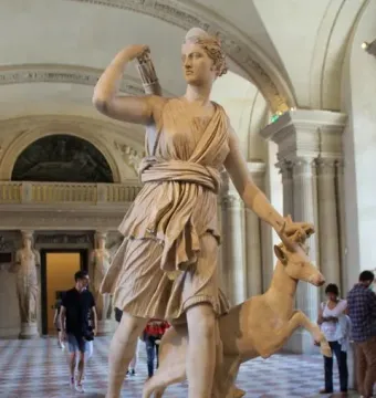 Diana of Versailles statue with a deer beside her in a museum gallery