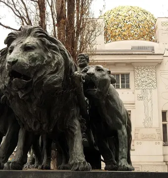 Marc Anton Group sculpture with lions pulling a chariot in front of a white building with a golden dome.