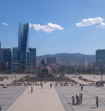 Damdin Sükhbaatar statue standing in a wide public square with pedestrians and modern buildings in the background.