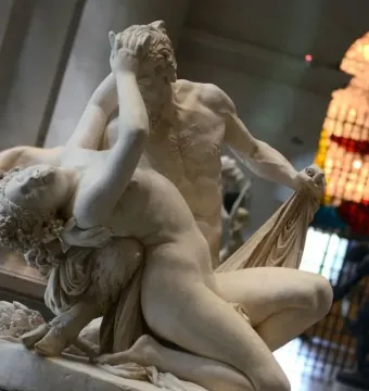 Satyre et bacchante sculpture of two figures embracing, with the male figure covering his face and the female figure reclining against him.