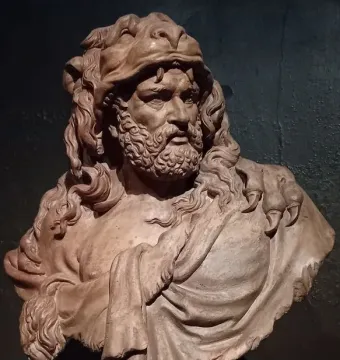 Clay bust of Hercules with a fur pelt draped over his shoulders and a bearded, determined face.
