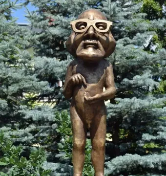 Citizen Włapko bronze statue of a male figure with a caricatured head, glasses, and a wide grin on a white pedestal.