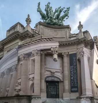 Immortality Overtaking Time sculpture mounted above a building facade with a chariot and rearing horses