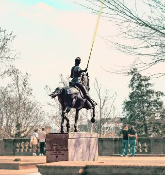 Joan of Arc equestrian statue with a raised yellow lance in a park setting