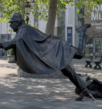 Vaartkapoen sculpture showing a bronze man in a helmet being pulled backward into a hole in the pavement.
