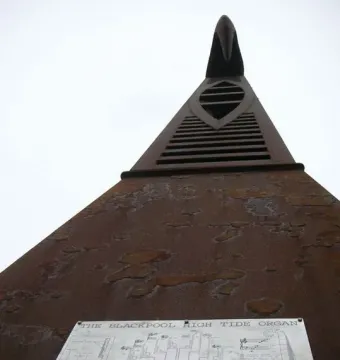 Blackpool High Tide Organ, a tall rust-brown metal sculpture with horizontal vents and an abstract crest at the top.