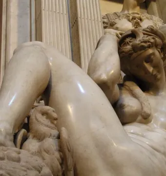 Michelangelo\'s Night, a reclining nude marble figure with her arm over her head beside a carved creature.