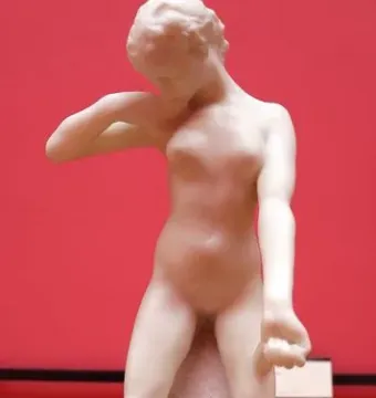 Standing Fauness, a marble nude female figure standing on a stone base with her head bowed and one hand at her neck.