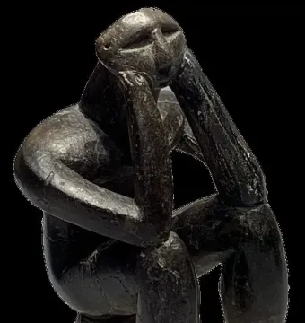 The Thinker of Cernavodă sculpture in a hunched seated pose with one hand supporting its head.
