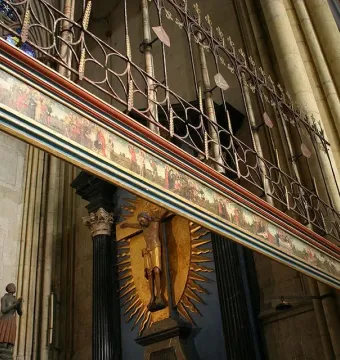 Gero Cross crucifix displayed high inside Cologne Cathedral beneath a painted frieze and ornate screen.