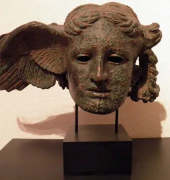 Bronze head of Hypnos with a wing on the side, shown on a black stand.