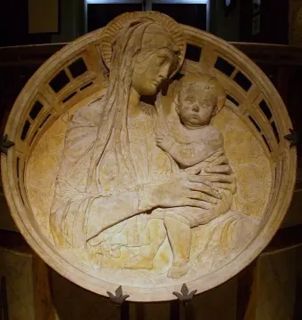 Madonna del Perdono relief showing a haloed mother holding a child, with cherubs in the background and a decorative border.