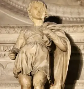 Marble statue of Saint Proculus standing in a short tunic and cloak among ornate stone carvings.