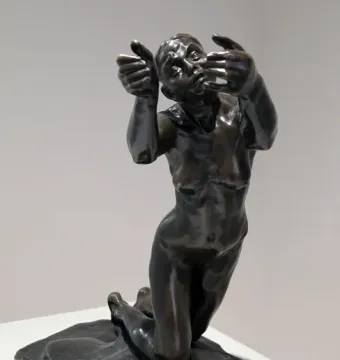 The Implorer bronze sculpture of a kneeling nude woman with raised hands and an upward gaze.