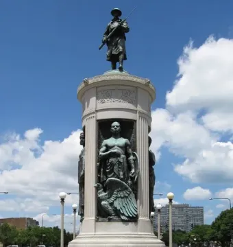 Victory Monument in Chicago with a bronze soldier statue atop a tall stone monument and figures in recessed niches below.