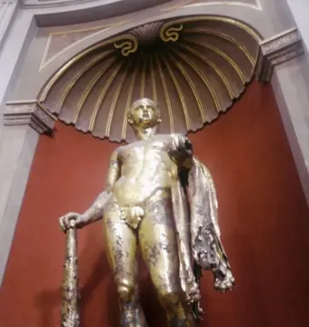 Gilded Hercules statue holding a club and wearing a lion skin, set in a decorative niche.
