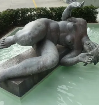 La Rivière by Aristide Maillol, a reclining nude female sculpture in a shallow pool with a small water jet nearby.