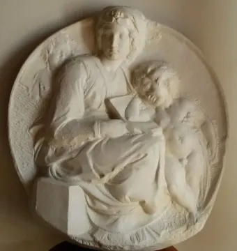 Pitti Tondo relief showing a seated woman holding a book with a child at her side and a smaller figure behind her shoulder.