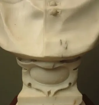 Lower portion of Cardinal Alessandro Peretti’s white marble bust, showing draped folds and a decorated pedestal base.