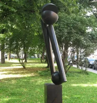 Große Zwei V, a dark abstract bronze sculpture on a plinth in a grassy outdoor setting.