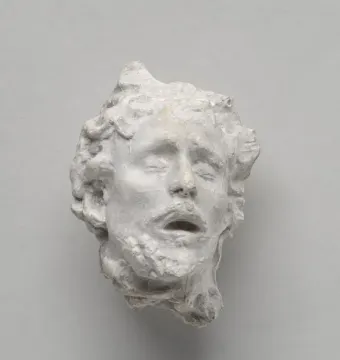Head of Saint John the Baptist sculpture with closed eyes and an open mouth, shown in a weathered white surface.