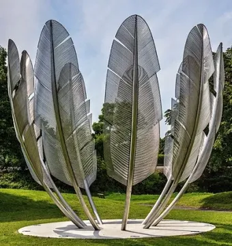 Kindred Spirits sculpture with tall silvery feather-like forms arranged in a circle on a grassy lawn.