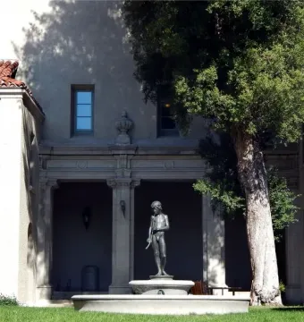 Spirit of Spanish Music, a bronze boy statue holding a long pipe-like instrument in a courtyard fountain.