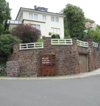 Dejudaization Institute Memorial metal panel with German text stands beside a stone wall.